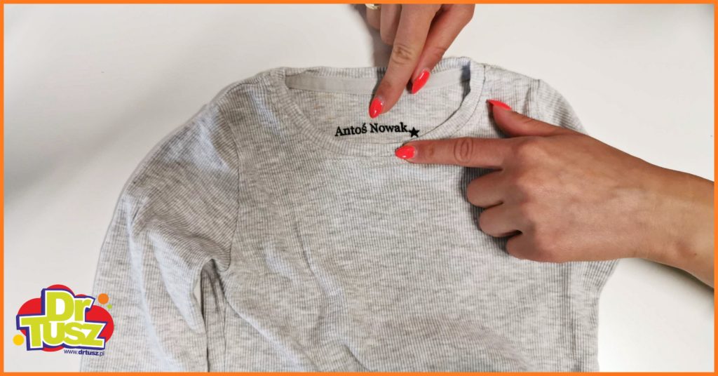 podpis Antosia Nowak zrobiony pieczątką do ubrań na szarej bluzce 