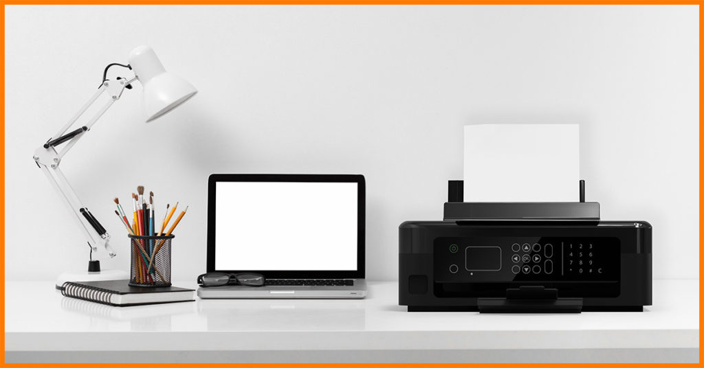 laptop, drukarka, zeszyt, lampka i przybory na biurku